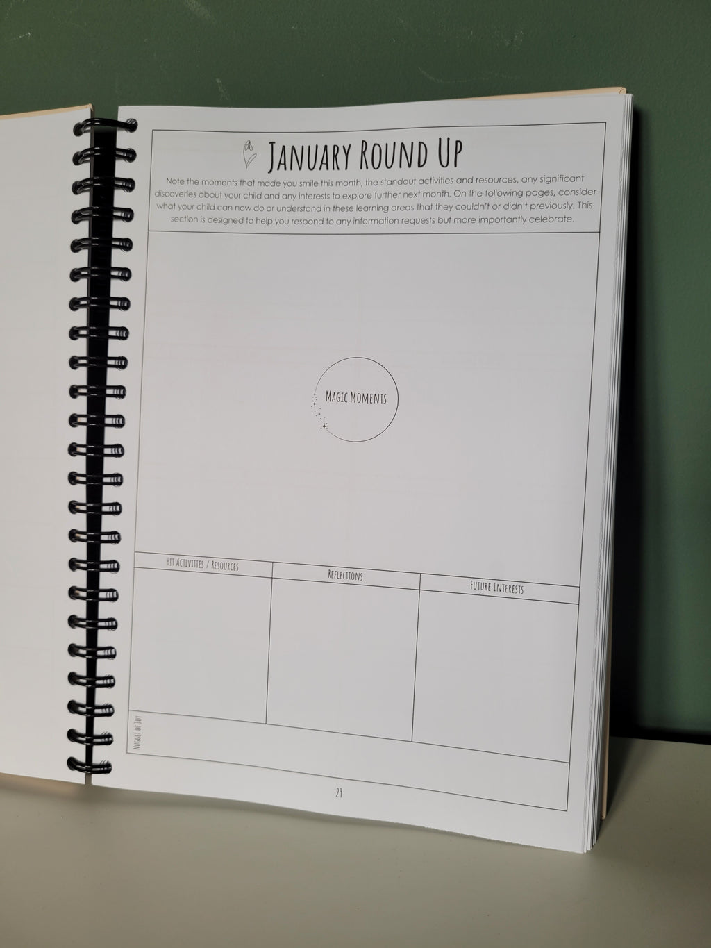 Spiral-bound planner open resting against a green wall