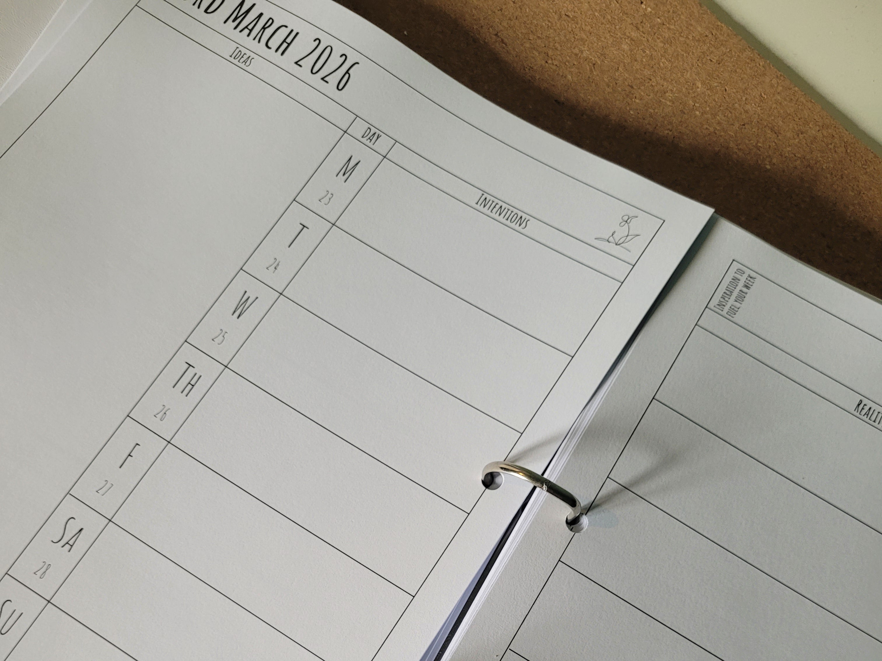 Open ring binder showing calendar page with a grid layout on a cork board background