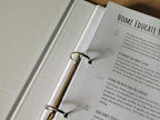 Open ring binder planner with text on a cork surface